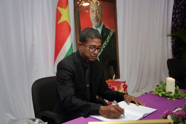 Suriname's Minister of Home Affairs, Delano Landvreugd, signs the condolence register of the late former President Desi Bouterse at the Ocer center in Paramaribo on December 30, 2024. The government of Suriname announced on December 28 that former President Desi Bouterse, who died while on the run from justice, will not receive a state funeral, said Foreign Minister Albert Ramdin. (Photo by Ranu Abhelakh / AFP)