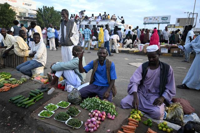 Men sell vegetables while people struggling to commute gather in Port Sudan as local transportation is strangled after government authorities reportedly changed two currency notes, invalidating old notes, on December 30, 2024, in the army-controlled Red Sea city city, where the government loyal to the army is based. Sudan is reeling from 20 months of fighting between the Sudanese army and the paramilitary Rapid Support Forces, led by rival generals, which have led to a dire humanitarian crisis. The war since April 2023 has killed tens of thousands of people and uprooted 12 million, creating what the United Nations has called the world's largest displacement crisis. (Photo by AFP)