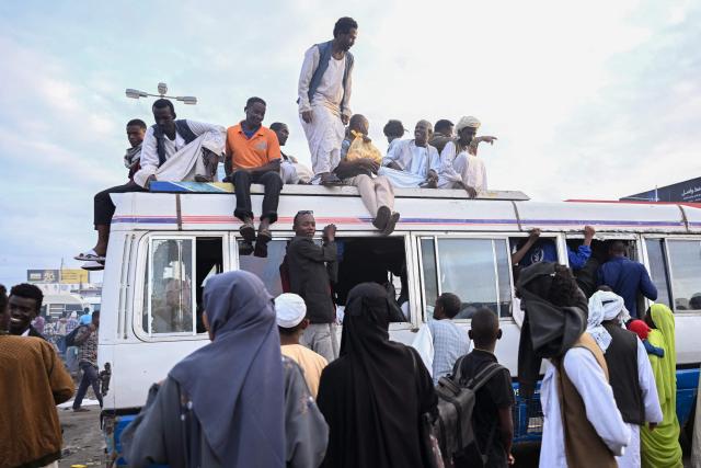 People struggling to commute gather around a packed bus in Port Sudan as local transportation is strangled after government authorities reportedly changed two currency notes, invalidating old notes, on December 30, 2024, in the army-controlled Red Sea city city, where the government loyal to the army is based. Sudan is reeling from 20 months of fighting between the Sudanese army and the paramilitary Rapid Support Forces, led by rival generals, which have led to a dire humanitarian crisis. The war since April 2023 has killed tens of thousands of people and uprooted 12 million, creating what the United Nations has called the world's largest displacement crisis. (Photo by AFP)