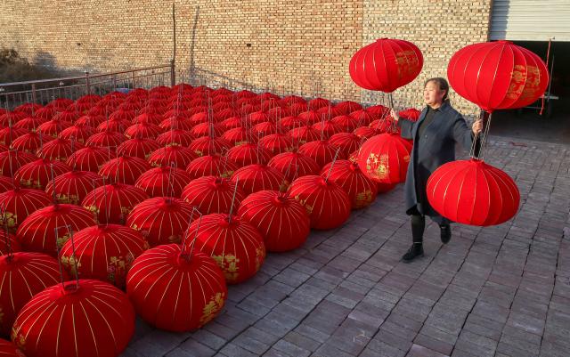 This photo taken on December 30, 2024 shows a woman putting out newly-made red lanterns in a factory at the Lantern Industrial Park of Yangzhao Village in Yuncheng, central China's Shanxi province, ahead of the Lunar New Year of the Snake. (Photo by AFP) / China OUT