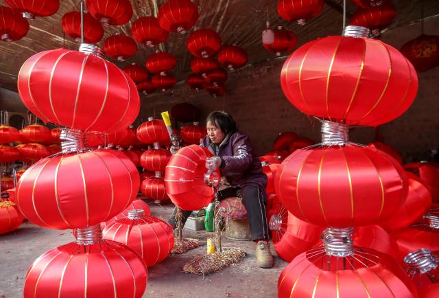 This photo taken on December 30, 2024 shows a woman making red lanterns in a factory at the Lantern Industrial Park of Yangzhao Village in Yuncheng, central China's Shanxi province, ahead of the Lunar New Year of the Snake. (Photo by AFP) / China OUT