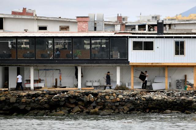 Workers salvage furniture at a restaurant damaged by strong waves that hit the seafront in La Serena, Chile, on December 30, 2024. Three deaths, one in Chile, have been blamed on large waves up to 13 feet (four metres) pummelling Ecuador, Chile and Peru, where nearly 100 ports have been closed because of the rough conditions. The phenomenon began on Christmas and is expected to last until January 1, according to Peru's National Emergency Operations Center. (Photo by Alejandro PIZARRO / AFP)