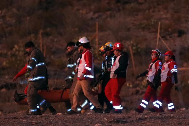 Firefighters and paramedics carry the body of a murdered National Institute of Migration (INM) agent, found on a hill near the Precos military checkpoint in the town of Samalayuca, municipality of Juarez, Chihuahua State, Mexico, on December 30, 2024. A Mexican immigration agent was killed on Monday in Juarez, on the US border, after asking a group of migrants to identify themselves, authorities said. (Photo by Herika MARTINEZ / AFP)