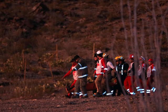 Firefighters and paramedics carry the body of a murdered National Institute of Migration (INM) agent, found on a hill near the Precos military checkpoint in the town of Samalayuca, municipality of Juarez, Chihuahua State, Mexico, on December 30, 2024. A Mexican immigration agent was killed on Monday in Juarez, on the US border, after asking a group of migrants to identify themselves, authorities said. (Photo by Herika MARTINEZ / AFP)