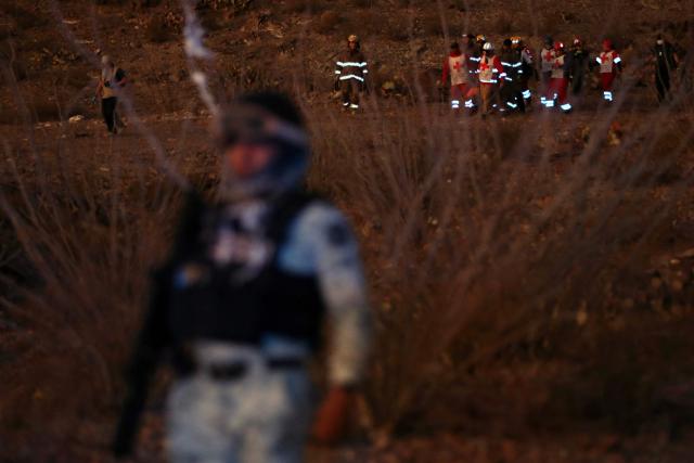 Firefighters and paramedics (top R) carry the body of a murdered National Institute of Migration (INM) agent, found on a hill near the Precos military checkpoint in the town of Samalayuca, municipality of Juarez, Chihuahua State, Mexico, on December 30, 2024. A Mexican immigration agent was killed on Monday in Juarez, on the US border, after asking a group of migrants to identify themselves, authorities said. (Photo by Herika MARTINEZ / AFP)