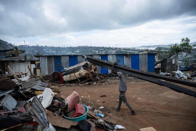 A man with salvaged metal bars to rebuild his home walks amidst houses in shanty town of a Cavani south district damaged by the cyclone Chido in the city of Mamoudzou, on the French Indian Ocean territory of Mayotte, on January 2, 2025. The most devastating cyclone to hit Mayotte in 90 years caused colossal damage on December 14, 2024 in France's poorest department. (Photo by JULIEN DE ROSA / AFP)