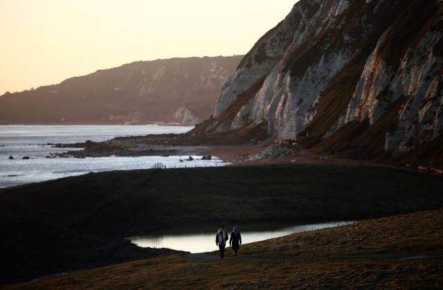 People walk in the late winter's sun on Samphire Hoe, west of Dover, on the south coast of England on January 2, 2025. (Photo by HENRY NICHOLLS / AFP)