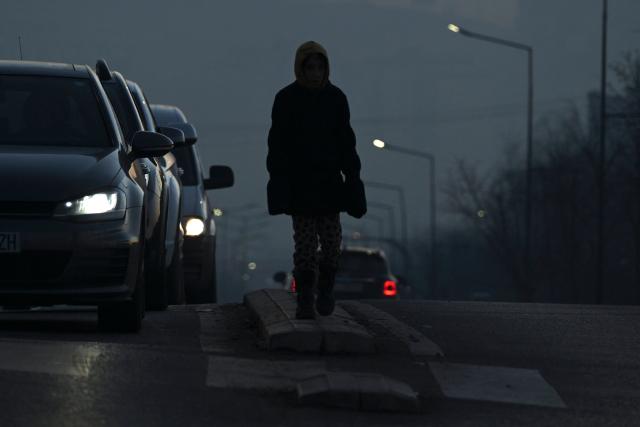 A young girl begs drivers for money in the thick smog of air pollution in Pristina, on January 2, 2025. (Photo by Armend NIMANI / AFP)