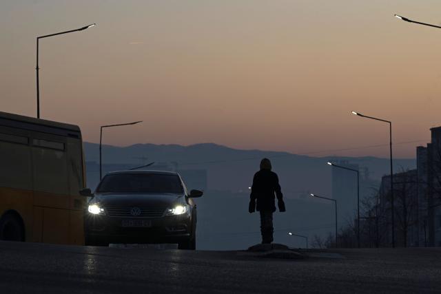 A young girl begs drivers for money in the thick smog of air pollution in Pristina, on January 2, 2025. (Photo by Armend NIMANI / AFP)