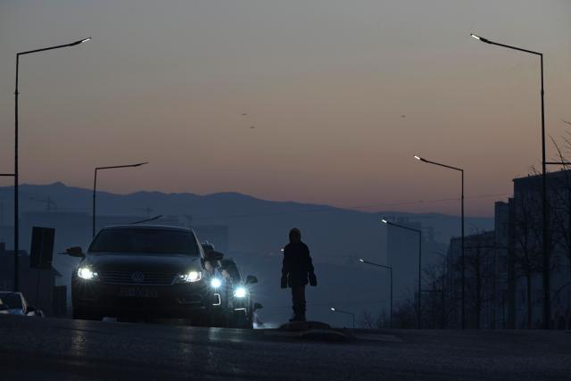 A young girl begs drivers for money in the thick smog of air pollution in Pristina, on January 2, 2025. (Photo by Armend NIMANI / AFP)