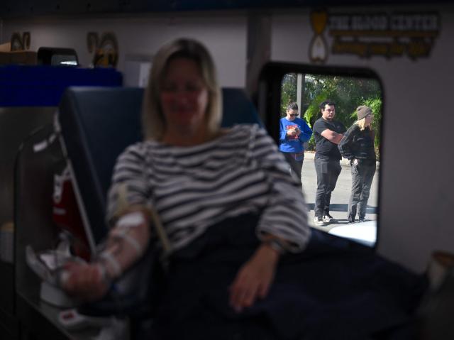 People wait in line as Lisa Weisdorffer (L) donates blood at the Blood Center on January 2, 2025 in New Orleans, Louisiana, following a terrorist attack on January 1. At least 15 people were killed and 30 injured on January 1 when a vehicle plowed overnight into a New Year's crowd in the heart of the thriving New Orleans tourist district, authorities in the southern US city said. (Photo by ANDREW CABALLERO-REYNOLDS / AFP)