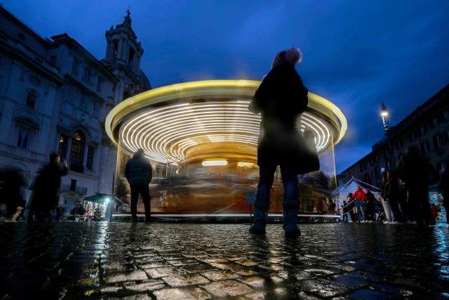 A woman watches a carousel as part of the Christmas and the Epiphany market in the Piazza Navona, in Rome on January 2, 2025. (Photo by Filippo MONTEFORTE / AFP)