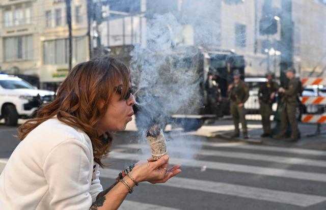 Stephanie Drake burns sage to cleanse the area on  Bourbon Street after it reopened to the public on January 2, 2025 in New Orleans, Louisiana, following a terrorist attack on January 1. At least 15 people were killed and 30 injured on January 1 when a vehicle plowed overnight into a New Year's crowd in the heart of the thriving New Orleans tourist district, authorities in the southern US city said. (Photo by ANDREW CABALLERO-REYNOLDS / AFP)