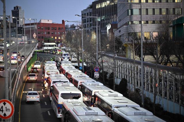 South Korean police vehicles (R) gather near the residence of South Korea's impeached President Yoon Suk Yeol in Seoul pon Jnuary 3, 2025. South Korea's impeached President Yoon Suk Yeol remained defiantly in his residence in Seoul on Thursday as investigators probing his ill-fated declaration of martial law sought to detain him for questioning. Investigators have an arrest warrant but Yoon's die-hard supporters, including far-right YouTube personalities, are gathering outside in a bid to protect him, setting up potential clashes with police and anti-Yoon protesters. (Photo by Philip FONG / AFP)