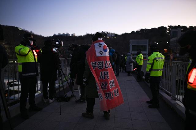 Police stand guard on the footbridge near the residence of South Korea's impeached President Yoon Suk Yeol in Seoul on January 3, 2025. South Korea's impeached President Yoon Suk Yeol remained defiantly in his residence in Seoul on Thursday as investigators probing his ill-fated declaration of martial law sought to detain him for questioning. Investigators have an arrest warrant but Yoon's die-hard supporters, including far-right YouTube personalities, are gathering outside in a bid to protect him, setting up potential clashes with police and anti-Yoon protesters. (Photo by Philip FONG / AFP)