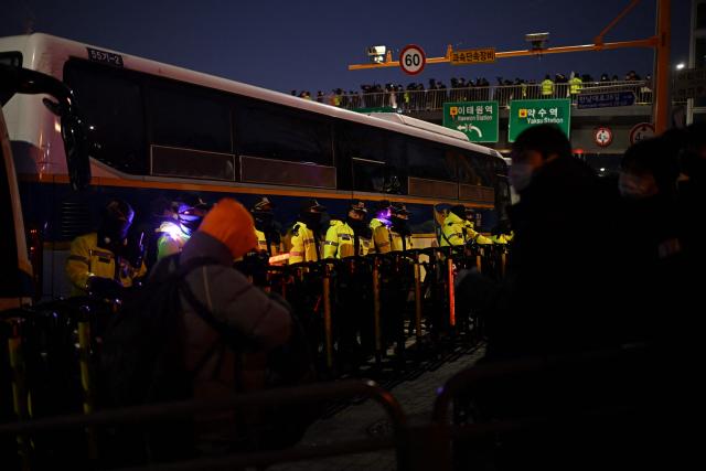 Police stand guard near the residence of South Korea's impeached President Yoon Suk Yeol as police vehicles gather in Seoul on January 3, 2025. South Korea's impeached President Yoon Suk Yeol remained defiantly in his residence in Seoul on Thursday as investigators probing his ill-fated declaration of martial law sought to detain him for questioning. Investigators have an arrest warrant but Yoon's die-hard supporters, including far-right YouTube personalities, are gathering outside in a bid to protect him, setting up potential clashes with police and anti-Yoon protesters. (Photo by Philip FONG / AFP)