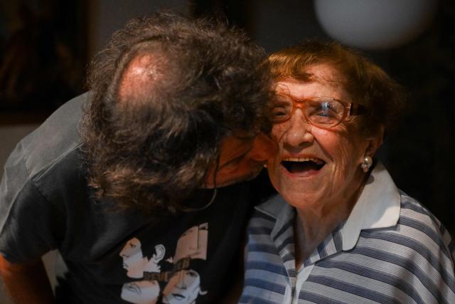 Holocaust survivor Lea Zajac de Novera, 98, receives a kiss from her son, Hector Novera, during an interview with AFP in Buenos Aires on January 2, 2025. Zajac de Novera was born in Michalowo, a town in the province of Bialystok, Poland, on December 31, 1926. At the beginning of the war, she lived with her family under Soviet occupation until 1942, when she and her family were relocated to the Pruzhany ghetto. In 1943 she was deported to the Auschwitz-Birkenau concentration camp, where she worked collecting rubble and sorting clothes of those killed in the gas chambers. (Photo by LUIS ROBAYO / AFP)