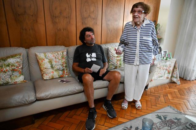 Holocaust survivor Lea Zajac de Novera, 98, gestures as she speaks next to her son, Hector Novera, during an interview with AFP in Buenos Aires on January 2, 2025. Zajac de Novera was born in Michalowo, a town in the province of Bialystok, Poland, on December 31, 1926. At the beginning of the war, she lived with her family under Soviet occupation until 1942, when she and her family were relocated to the Pruzhany ghetto. In 1943 she was deported to the Auschwitz-Birkenau concentration camp, where she worked collecting rubble and sorting clothes of those killed in the gas chambers. (Photo by LUIS ROBAYO / AFP)