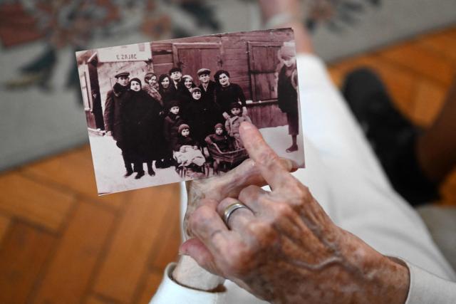 Holocaust survivor Lea Zajac de Novera, 98, shows a picture of her family as she speaks during an interview with AFP in Buenos Aires on January 2, 2025. Zajac de Novera was born in Michalowo, a town in the province of Bialystok, Poland, on December 31, 1926. At the beginning of the war, she lived with her family under Soviet occupation until 1942, when she and her family were relocated to the Pruzhany ghetto. In 1943 she was deported to the Auschwitz-Birkenau concentration camp, where she worked collecting rubble and sorting clothes of those killed in the gas chambers. (Photo by LUIS ROBAYO / AFP)