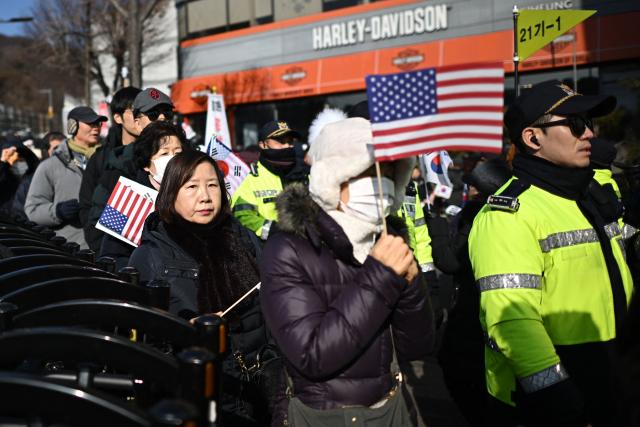 Supporters of South Korea's impeached President Yoon Suk Yeol hold US flags as they gather near his residence in Seoul on January 3, 2025. South Korean investigators attempted to arrest impeached President Yoon at his residence on January 3 over a failed martial law bid, but security forces were blocking their efforts. (Photo by Philip FONG / AFP)