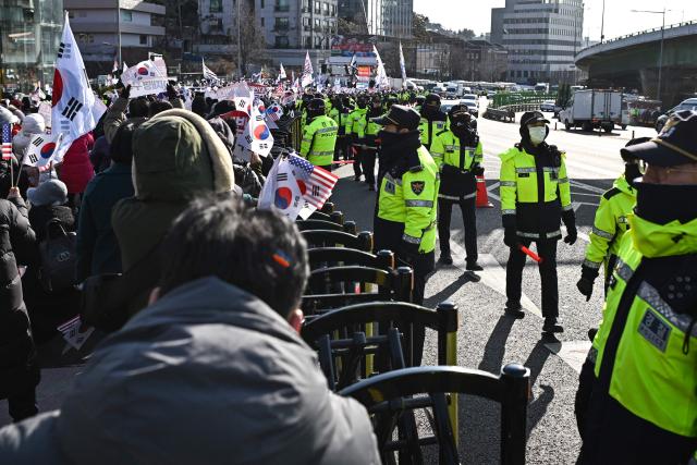 Police keep watch over supporters of South Korea's impeached President Yoon Suk Yeol gathered near his residence in Seoul on January 3, 2025. South Korean investigators attempted to arrest impeached President Yoon at his residence on January 3 over a failed martial law bid, but security forces were blocking their efforts. (Photo by Philip FONG / AFP)