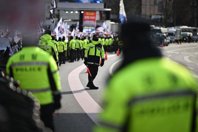 Police keep watch over supporters of South Korea's impeached President Yoon Suk Yeol gathered near his residence in Seoul on January 3, 2025. South Korean investigators attempted to arrest impeached President Yoon at his residence on January 3 over a failed martial law bid, but security forces were blocking their efforts. (Photo by Philip FONG / AFP)