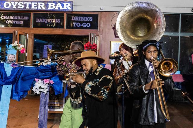 A band plays next to crosses with pictures of victims at a memorial on Bourbon Street after it reopened to the public on January 2, 2025, in New Orleans, Louisiana, following an attack on January 1 which left 14 dead. A US army veteran loyal to the Islamic State jihadist group likely acted alone when he killed 14 and injured dozens in a truck attack on a crowd of New Year revelers in New Orleans, the FBI said on January 2. (Photo by ANDREW CABALLERO-REYNOLDS / AFP)