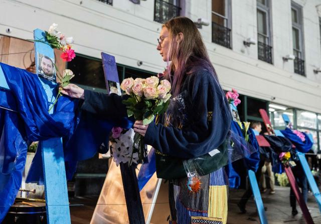 A woman places flowers on crosses with pictures of victims at a memorial on Bourbon Street after it reopened to the public on January 2, 2025, in New Orleans, Louisiana, following an attack on January 1 which left 14 dead. A US army veteran loyal to the Islamic State jihadist group likely acted alone when he killed 14 and injured dozens in a truck attack on a crowd of New Year revelers in New Orleans, the FBI said on January 2. (Photo by ANDREW CABALLERO-REYNOLDS / AFP)