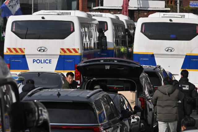 Anti-corruption investigators and police enter vehicles after leaving the residence of South Korea's impeached President Yoon Suk Yeol in Seoul on January 3, 2025 after calling off their attempt to arrest Yoon. South Korea investigators called off their attempt to arrest impeached President Yoon Suk Yeol at his residence on January 3 over a failed martial law bid, citing safety concerns after a standoff with his security team. (Photo by JUNG Yeon-je / AFP)