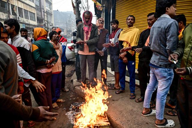 Men gather around a bonfire along a street on a cold winter morning in Guwahati on January 3, 2025. (Photo by Biju BORO / AFP)