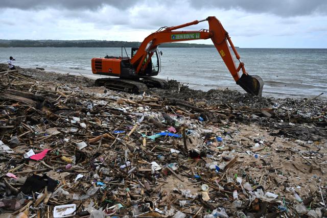 Workers clear plastic waste and other garbage washed ashore that has accumulated thickly at a beach in Kedonganan Badung regency, on the resort island of Bali on January 3, 2025. (Photo by SONNY TUMBELAKA / AFP)