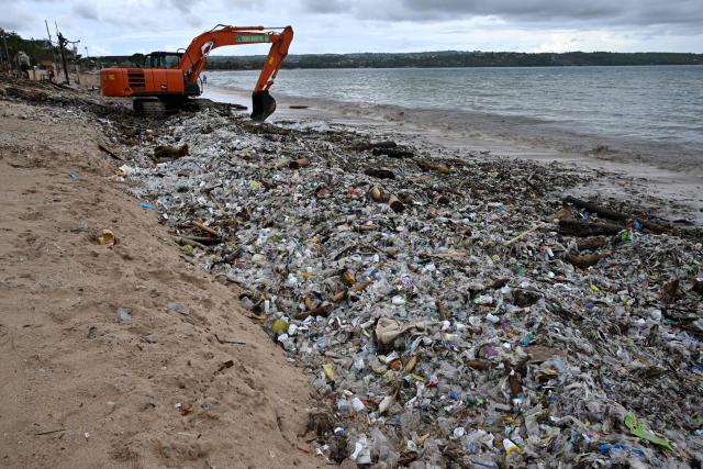 Workers clear plastic waste and other garbage washed ashore that has accumulated thickly at a beach in Kedonganan Badung regency, on the resort island of Bali on January 3, 2025. (Photo by SONNY TUMBELAKA / AFP)