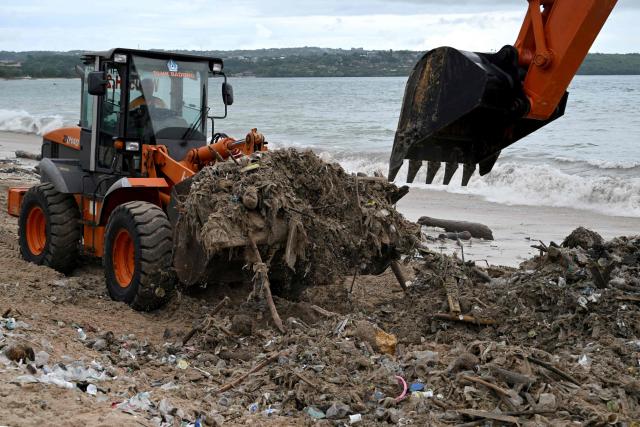 Workers clear plastic waste and other garbage washed ashore that has accumulated thickly at a beach in Kedonganan Badung regency, on the resort island of Bali on January 3, 2025. (Photo by SONNY TUMBELAKA / AFP)