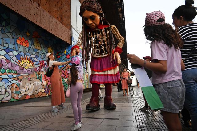 A child interacts with Little Amal, a 12-foot-tall puppet representing a ten-year-old Syrian refugee, during a performance at the Gabriel Mistral Cultural Center as part of the opening of the 32nd version of the International Festival Teatro a Mil in Santiago on January 3, 2025. Santiago a Mil International Theatre Festival is an annual performing arts festival that takes place in January in Santiago, Chile. It is the largest arts festival in Chile and includes theatre, dance, and music events from Chile and abroad, performed in the capital city, Santiago, and around the country. (Photo by RODRIGO ARANGUA / AFP)