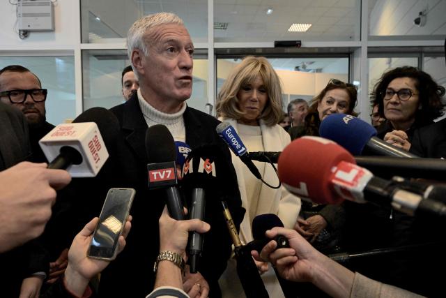 French national football team's head coach Didier Deschamps (front L) and French President's wife Brigitte Macron (front C) stand outside Bordeaux's main post office in Bordeaux, southwestern France, on January 8, 2025, as they launch the 2025 edition of the charity fund called "Operations pieces jaunes" (operation yellow coins), with its foundation aiming to improve the conditions of hospitalized children. France's 2018 World Cup-winning head coach Didier Deschamps announced on January 8, 2025 he will leave his post after the 2026 finals. (Photo by Philippe Lopez / AFP)