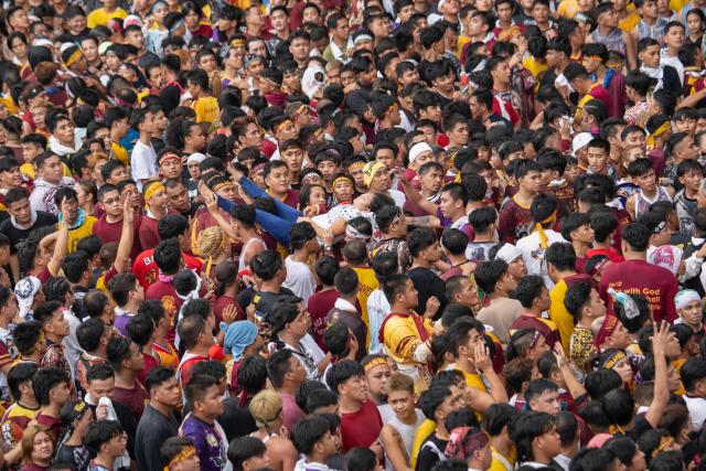 TOPSHOT - Catholic devotees carry a woman (C) who collapsed during the annual religious procession of the Black Nazarene in Manila on January 9, 2025. Hundreds of thousands of Catholic pilgrims swarmed the streets of Manila in search of a miracle on January 9, straining to reach a centuries-old statue of Jesus Christ in an annual display of religious fervour. (Photo by Ted ALJIBE / AFP)