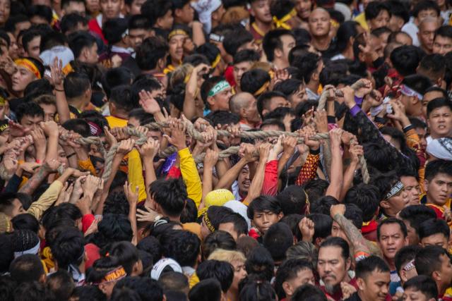 Catholic devotees holds up a rope guiding the carriage carrying the statue of the Black Nazarene during the annual religious procession in Manila on January 9, 2025. Hundreds of thousands of Catholic pilgrims swarmed the streets of Manila in search of a miracle on January 9, straining to reach a centuries-old statue of Jesus Christ in an annual display of religious fervour. (Photo by Ted ALJIBE / AFP)