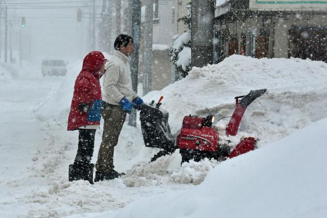 A man uses a snowblower to clear a path after high drifts of snow built up along a street in the northern Japanese city of Aomori on January 9, 2025. Local media reported on January 9 that the Japan Meteorological Agency was urging caution due to heavy snows expected along the Sea of Japan and mountainous areas. (Photo by JIJI Press / AFP) / Japan OUT