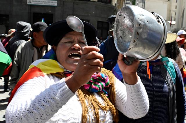 A supporter of Bolivia's former president (2006-2019), Evo Morales, bangs a pot during the ‘Communal for Life’ march against the government of Luis Arce and to denounce the economic crisis outside the vice-presidency building in La Paz on January 13, 2025. The supporters of ex-president Morales march are also calling for the release of 90 people who have been detained since last year roadblocks, and plan to arrive in La Paz on January 13. (Photo by JORGE BERNAL / AFP)