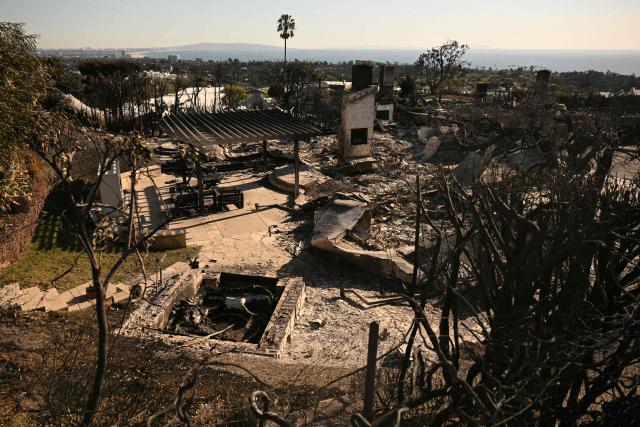 Fireplaces and chimneys stand amid the ruins of a home in the Pacific Palisades neighborhood of Los Angeles, California, on January 13, 2025 after the area was largely devastated by the Palisades Fire. Firefighters were battling massive wildfires on January 13 that have ravaged Los Angeles and killed at least 24 people, with officials warning of incoming dangerous winds that could whip up the blazes further. (Photo by Patrick T. Fallon / AFP)