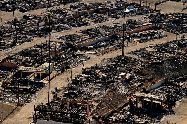 Charred homes and burnt cars are pictured amid the rubble of the fire-ravaged Pacific Palisades Bowl Mobile Estates in Los Angeles, California, on January 13, 2025. Firefighters were battling massive wildfires on January 13 that have ravaged Los Angeles and killed at least 24 people, with officials warning of incoming dangerous winds that could whip up the blazes further. (Photo by AGUSTIN PAULLIER / AFP)