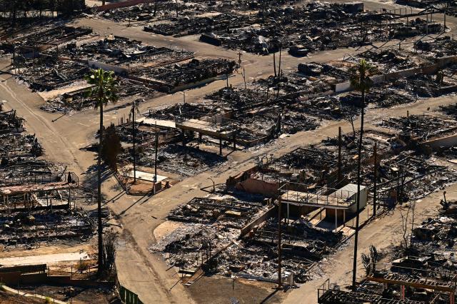 Charred homes and burnt cars are pictured amid the rubble of the fire-ravaged Pacific Palisades Bowl Mobile Estates in Los Angeles, California, on January 13, 2025. Firefighters were battling massive wildfires on January 13 that have ravaged Los Angeles and killed at least 24 people, with officials warning of incoming dangerous winds that could whip up the blazes further. (Photo by AGUSTIN PAULLIER / AFP)