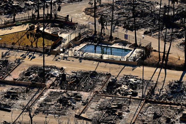 A swimming pool sits amid charred homes and burnt cars in the rubble of the fire-ravaged Pacific Palisades Bowl Mobile Estates in Los Angeles, California, on January 13, 2025. Firefighters were battling massive wildfires on January 13 that have ravaged Los Angeles and killed at least 24 people, with officials warning of incoming dangerous winds that could whip up the blazes further. (Photo by AGUSTIN PAULLIER / AFP)