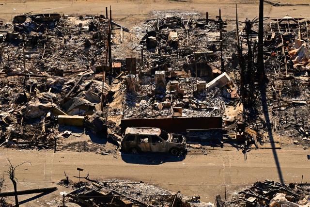 Charred homes and burnt cars are pictured amid the rubble of the fire-ravaged Pacific Palisades Bowl Mobile Estates in Los Angeles, California, on January 13, 2025. Firefighters were battling massive wildfires on January 13 that have ravaged Los Angeles and killed at least 24 people, with officials warning of incoming dangerous winds that could whip up the blazes further. (Photo by AGUSTIN PAULLIER / AFP)