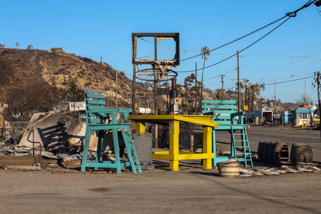 A burned sign is seen above a sculpture of a large table and chairs outside Rosenthal Wine Bar & Patio on Pacific Coast Highway on January 14, 2025, Malibu, California, in the aftermath of the Palisades Fire. Powerful winds forecast for late January 14 threatened to whip up massive fires that are still burning around Los Angeles in a tragedy that has killed at least 25 people and badly shaken the city. (Photo by VALERIE MACON / AFP)