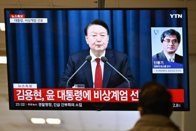 (FILES) A man watches South Korea's President Yoon Suk Yeol speak during a news broadcast on a television at a train station in Seoul on December 3, 2024, after he declared emergency martial law, saying the step was necessary to protect the country from "communist forces" amid parliamentary wrangling over a budget bill. Impeached South Korean leader Yoon Suk Yeol was arrested on January 15, 2025 over his failed martial law bid, ending a weeks-long standoff with authorities and becoming the first president to be detained in the nation's history. (Photo by Anthony WALLACE / AFP)