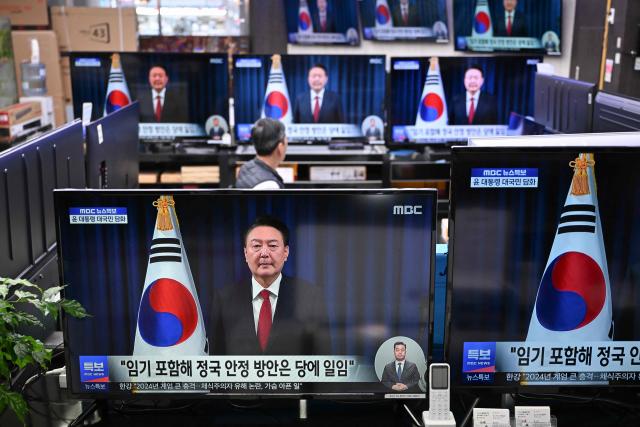 (FILES) Television screens show live footage of an address by South Korea's President Yoon Suk Yeol, at an electronic market in Seoul on December 7, 2024. Impeached South Korean leader Yoon Suk Yeol was arrested on January 15, 2025 over his failed martial law bid, ending a weeks-long standoff with authorities and becoming the first president to be detained in the nation's history. (Photo by JUNG Yeon-je / AFP)