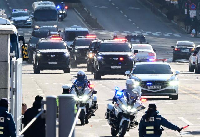 A motorcade carrying impeached South Korea President Yoon Suk Yeol arrives at the complex building housing the Corruption Investigation Office for High-ranking Officials (CIO) in Gwacheon on January 15, 2025, after Yoon was arrested over his failed martial law bid. (Photo by KOREA POOL / AFP) / South Korea OUT