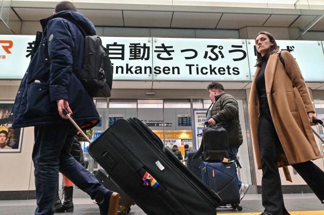 Travellers walk with their bags through Tokyo station on January 15, 2025. Japan is expected to announce tourist figures for the year 2024 later in the day on January 15, widely expected to break the record set in 2019. (Photo by Richard A. Brooks / AFP)