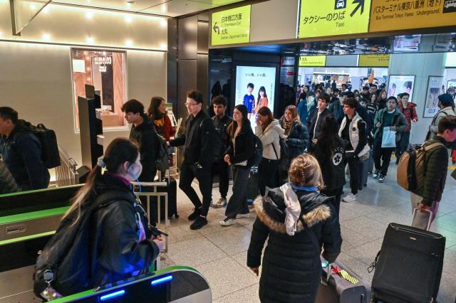 Travellers queue up with their bags to go through the gates of the high speed rail system at Tokyo station on January 15, 2025. Japan is expected to announce tourist figures for the year 2024 later in the day on January 15, widely expected to break the record set in 2019. (Photo by Richard A. Brooks / AFP)